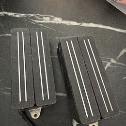 Dvě černé humbuckery s kovovými póly. Povrch je matně černý a vykazuje drobné oděrky a známky opotřebení. Na snímačích nejsou viditelné žádné značky…
