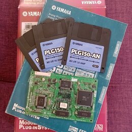 Fotografie zobrazuje červenobílý karton s nápisem YAMAHA PLG150-AN Plug-in Board, modrou obálku s logem YAMAHA a čtyři 3,5" diskety. Na disketách je…