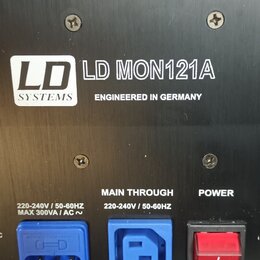 Detail zadní strany černého elektronického zařízení s kovovým povrchem. Je zde uveden nápis LD SYSTEMS, model LD MON121A a text ENGINEERED IN GERMANY…