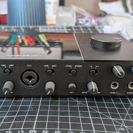 Černý zvukový interface s nápisem KOMPLETE AUDIO 6 na horní straně. Přední panel obsahuje dva kombinované vstupy (IN 1, IN 2), přepínače LINE/INST a…