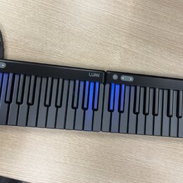 Černá elektronická klaviatura tvořená dvěma spojitými moduly. Na horní hraně obou částí je bílý nápis LUMI a ovládací tlačítka. Některé klávesy jsou…
