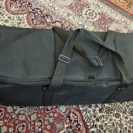 Černý textilní pouzdro (gig bag) obdélníkového tvaru s dvěma nosními popruhy. Povrch materiálu vykazuje drobné nečistoty a opotřebení. Na pouzdře nej…