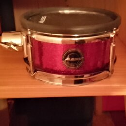 Elektronický snare s fialovým třpytivým povrchem a chromovanými obručemi. Na přední straně je viditelné logo ALESIS v kruhovém medallionu a stejný ná…