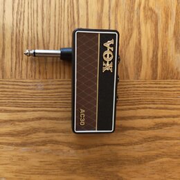 Kytarový kabel s konektorem v hnědém a černém provedení. Na povrchu je zlatým nápisem značka VOX a model AC30. Povrch hnědé části má kosočtvercový vz…