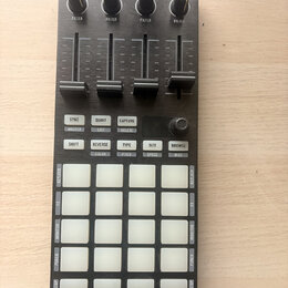 Černý MIDI kontrolér s nápisy TRAKTOR a NI v horní části. Zařízení obsahuje čtyři posuvníky s označením FILTER, pět řad bílých podsvícených tlačítek…
