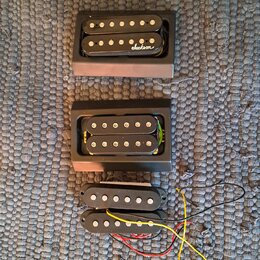 Tři kytarové humbuckery v černé barvě. Horní snímač má na krytu bílý nápis Jackson v rukopisném stylu. Střední snímač je umístěn v černé plastové rám…