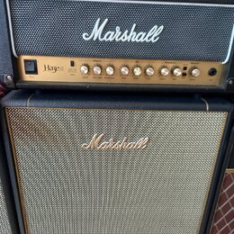 Kytarový zesilovač a reproduktorové boxy značky Marshall. Horní kombo má zlatý ovládací panel s nápisem Haze 100 a sekcemi Effects, EQ a Overdrive. S…