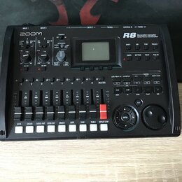 Černý digitální sekvenční přístroj značky ZOOM, model R8 s nápisem Recorder:Sampler Interface:Controller. Zařízení obsahuje displej, několik ovládací…