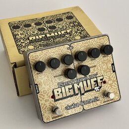 Kytarový efekt v kovovém šasi s béžovým povrchem a ozdobným vzorem. Na pedálu je nápis „Germanium 4 BIG MUFF“ a logo „electro-harmonix“. Jsou zde ovl…