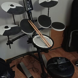 Elektronická bicí souprava s černým rámem a bílo-černými činely. Na modulu je viditelné logo Roland a označení TD-1. Na snareu je nápis Roland, na pa…