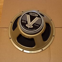 Kruhové reproduktory v zlatavém kovovém rámu s černou membránou. Na středovém krytu je nápis CELESTION, velký symbol V a text G12 TYPE 70-watt oraz C…