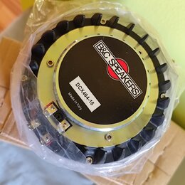 Reproduktor v průhledném plastovém obalu. Na zadní straně je černý štít s bílým nápisem B&C SPEAKERS a červeným logem, pod ním bílá nálepka s textem…