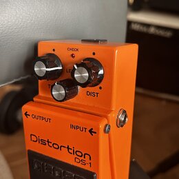 Oranžový kytarový efekt s nápisy Distortion DS-1 a logem BOSS na spodním černém pedálu. Na horní části jsou tři ovládací knoflíky s popisky LEVEL, DI…