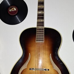 Akustická kytara s polodubovou konstrukcí v tmavě hnědém sunburst provedení. Na těle jsou viditelné dva f-otvory a kovový most. Na hlavě nástroje je…