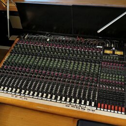 Velký míchací pult s dřevěným rámem a černým ovládacím panelem. Na pravé straně je nápis TOFT AUDIO CONSOLE MTO a logo Toft Audio Design. Panel obsah…