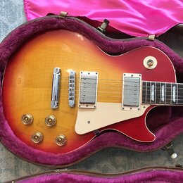 Elektrická kytara s tónem sunburst (červená a žlutá) v hnědém kufru s fialovou výstýlkou. Nástroj má dva humbuckery, čtyři zlaté ovládací knoflíky a…