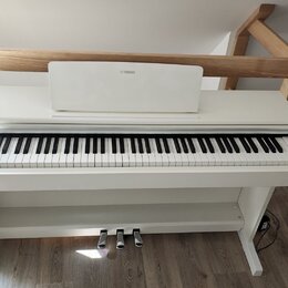 Bílé digitální piano s bílým stojanem a třemi pedály. Na hudebním stojanu je umístěno logo YAMAHA. Nástroj vykazuje čistý povrch bez viditelných pošk…
