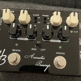 Černý kytarový efekt s nápisem Acoustic Preamp a logem HB. Zařízení má čtyři bílé otočné knoflíky, čtyři černé přepínače a dvě stříbrné tlačítka ozna…