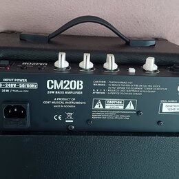 Zadní strana černého basového komba s nápisem CM20B 20W BASS AMPLIFIER a logem Cort. Na štítku je uveden vstupní napětí 220-240V~50/60Hz a Serial Num…