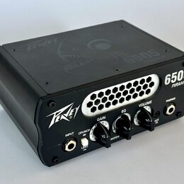Černý kytarový zesilovač s nápisy Peavey a 6505 PIRANHA. Na předním panelu jsou knofíky GAIN, EQ a VOLUME, přepínače CRUNCH/LEAD a NOTCH, vstup INPUT…