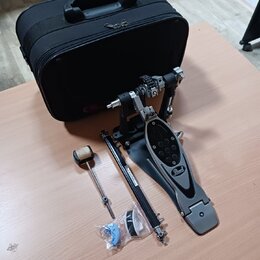 Na fotografii je černý basový pedál s logem Pearl na šlapce a doprovodný černý kufr. K pedálu jsou přiloženy volné části: beater s plstěnou hlavou, k…