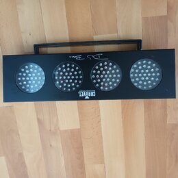 Černý obdélníkový LED panel s čtyřmi kulatými svítícími plochami a madlem na horní straně. Na spodní hraně je bílý nápis CHAUVET a pod ním menší text…