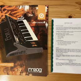 Fotografie zobrazuje uživatelskou příručku a doprovodný printed list v češtině k syntetizátoru. Na obálce manuálu je nápis USER'S MANUAL a v dolní čá…