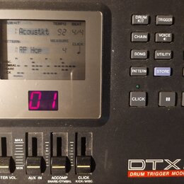 Černý elektronický modul s displejem a ovládacími prvky. Na spodní části je bílý nápis DTX Version 2.0 a pod ním červený pruh s textem DRUM TRIGGER M…