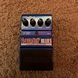 Modrý kytarový efekt s nápisy SCREAMIN' BLUES a OVERDRIVE/DISTORTION. Na pravé straně jsou čtyři ovládací knoflíky s popisky LEVEL, LOW, HIGH a GAIN…