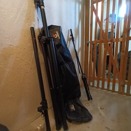 Na fotografii jsou tři černé rozkládací stojany a jeden černý textilní pouzdro opřené o stěnu. Na pouzdře je nápis „besponte“ doprovázený červeným lo…