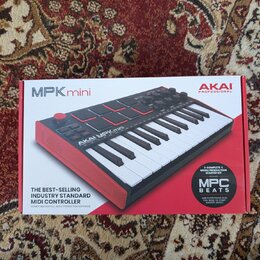 Fotografie zobrazuje krabici od MIDI kontroléru AKAI MPK mini. Na balení je zobrazen červený nástroj s klávesami a padem, doprovázený nápisy AKAI PRO…