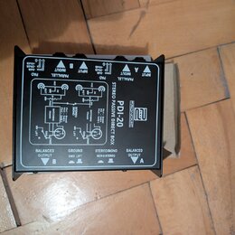 Černá pasivní DI box s nápisem STEREO PASSIVE DIRECT BOX a označením modelu PDI-20 pod logem PRONOMIC. Zařízení má na horní straně přepínače PAD a PA…