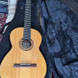 Kytara s nylonovými strunami v černém pouzdře. Na štítku uvnitř otvoru je nápis „Classical Guitar“ a pod ním podpis „Luthier Washik“. Tělo kytary je…