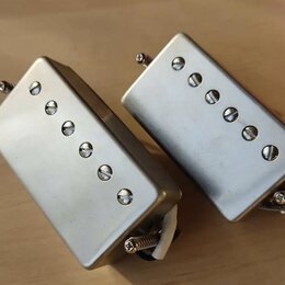 Dvě stříbrné humbuckerové snímače s kovovým krytem. Každý snímač má v horní části šest viditelných šroubů. Na krytech nejsou žádné viditelné značky a…