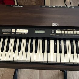 Hnědý elektronický orgán s klaviatura v dřevěném provedení. Na ovládacím panelu jsou nápisy XK-2 a HAMMOND. Jsou zde vidět bílé klávesy, tahové přepí…