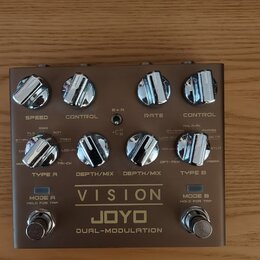 Kytarový efekt pedál v šedé barvě s kovovým povrchem. Na spodní části je nápis VISION, JOYO a DUAL-MODULATION. Zařízení má osm ovládacích knoflíků, d…