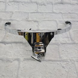 Chromovaný kovový držák na činely s polokruhovým ramenem. Na středovém trojúhelníkovém prvku je viditelné logo "Gibson". Předmět vykazuje mírné opotř…