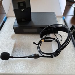 Sada bezdrátového mikrofonu v bílém polystyrenovém boxu. Obsahuje černý vysílač s logem Sennheiser a nápisem XS WIRELESS SENNHEISER, černý přijímač s…