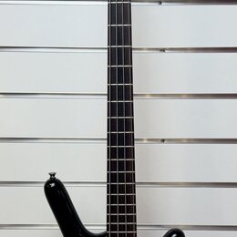 Čtyřstrunná elektrická basová kytara s tmavým, gradientním lakem v černě a hnědě. Na hlavě je bílý nápis RedBass. Nástroj má tmavý hmatník a dvě sním…