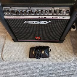 Černý kytarový kombo zesilovač s nápisy TRANSTUBE SERIES, STUDIO PRO 112 a PEAVEY. Na spodní části mřížky je červené logo ve tvaru stylizedého písmen…