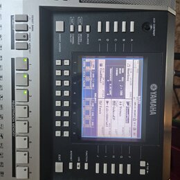 Detailní záběr na ovládací panel digitálního klavíru značky YAMAHA. Uprostřed je LCD displej zobrazující nastavení s nápisy jako NewSong, Cool8Beat a…