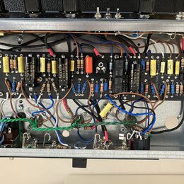 Fotografie zachycuje vnitřek elektronického zařízení s otevřeným šasi. Je viditelná černá základní deska osazená různými komponenty, jako jsou rezist…