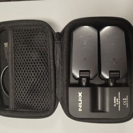 Černý přepravní pouzdro s dvěma bezdrátovými vysílači vloženími. Na spodní části pouzdra je bílý nápis NUX a text C-SRC 5.8G WIRELESS SYSTEM, CE, MAD…