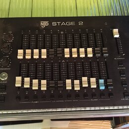 Černý ovládací panel s nápisem NJD STAGE 2. Zařízení obsahuje dvě řady posuvníků, několik otočných knoflíků a tlačítek s popisky jako FADE, PROGRAM,…