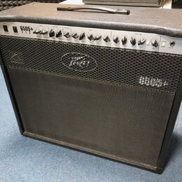 Kytarový kombo zesilovač s černým potahem a stříbrným ovládacím panelem. Na panelu je nápis 6505+ 112 a logo Peavey. Přední mřížka je černá s vyšívan…