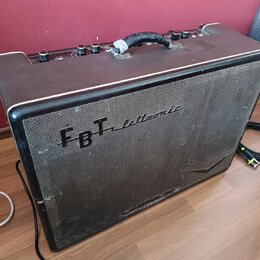Černý kytarový kombo zesilovač s látkovou maskou reproduktoru. Na přední straně je nápis FBT elettronice. Horní panel obsahuje ovládací knoflíky a ru…