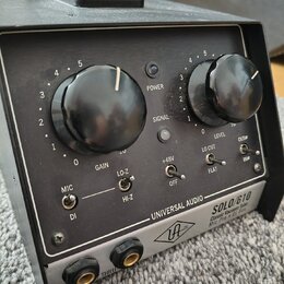 Černý rackový přístroj s nápisem UNIVERSAL AUDIO SOLO/610 Classic Vacuum Tube Mic Pre & DI Box. Přední panel obsahuje dva velké černé otočné ovladače…