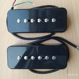 Dvě černé kytarové humbuckery s kovovými ladicími šrouby. Nástroje jsou provedeny v černé barvě s lesklým povrchem, na kterém jsou viditelné drobné š…
