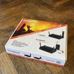 Kartonová krabice s oranžovým potiskem, na které je nápis VHF wireless microphone · radiomicrofono VHF a značka bespeco. Na obalu jsou zobrazeny dva…