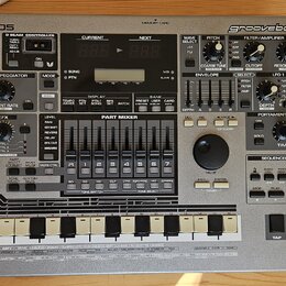 Stříbrný sekvenční sampler Roland MC-505 groovebox. Na předním panelu jsou viditelné nápisy Roland MC-505 a groovebox, řada ovládacích knoflíků, posu…